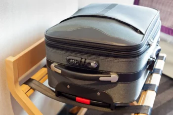 A suitcase stand in a hotel room with a suitcase sitting on it to keep it off the ground.