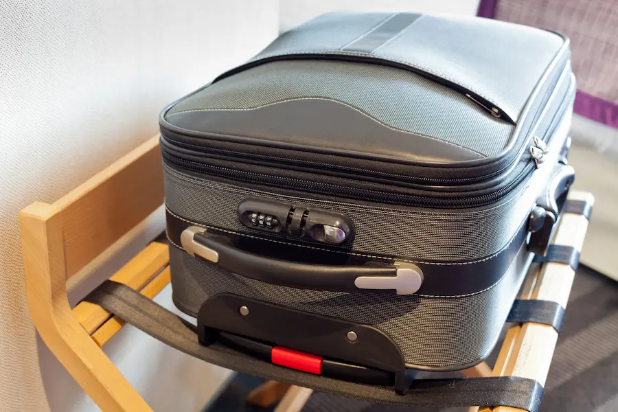 A suitcase stand in a hotel room with a suitcase sitting on it to keep it off the ground.