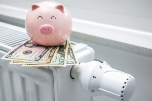 Piggy bank sitting on several bills of cash, balanced on radiator