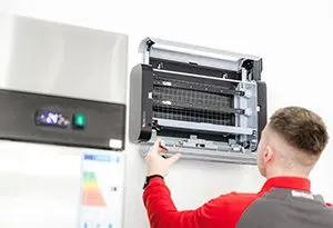 A pest control technician installs a Lumnia LED fly trap in a commercial kitchen