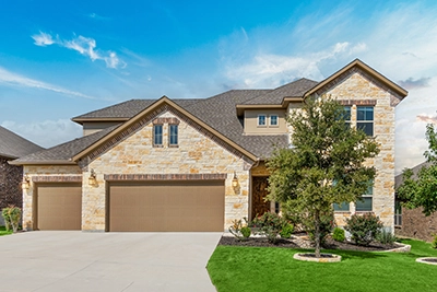 A suburban home with brick siding and a lush green lawn.