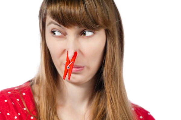 Woman wearing clothes pin on her nose so she won't have to smell - signs you have a pest infestation