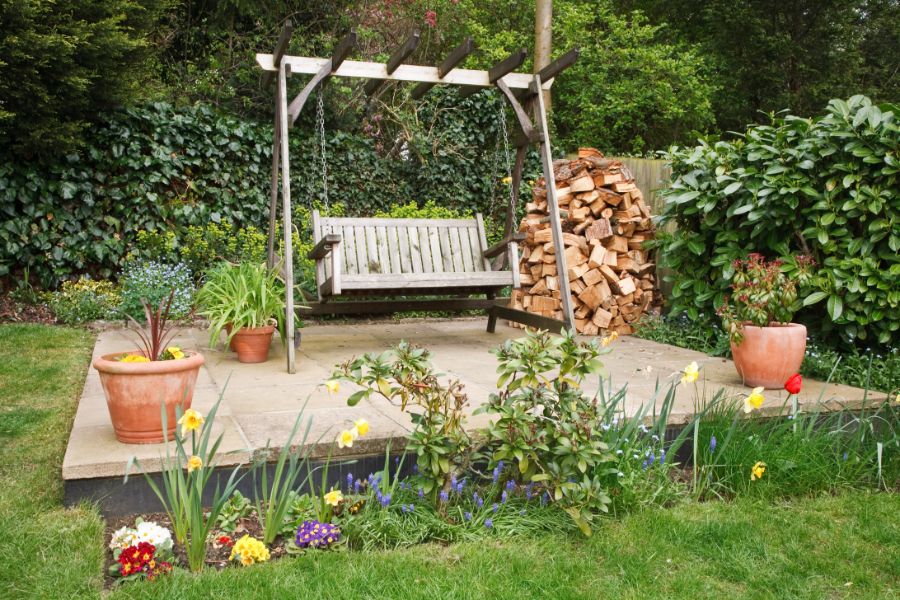 A wooden patio swing in a garden.